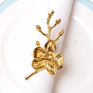 Elegant gold orchid napkin ring with glossy finish on white napkin and blue plate