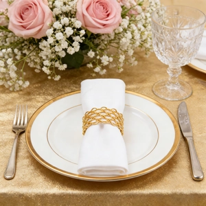 Elegant gold woven chain napkin ring on white fabric napkin for luxury dining decor