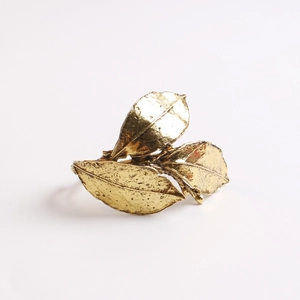 Antique gold olive leaf napkin ring with intricate textured veins on a white background