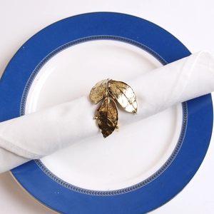 Golden olive leaf napkin ring with lifelike texture on a white plate and napkin