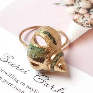 Elegant conch shell ring with gold trim on a decorative secret garden background