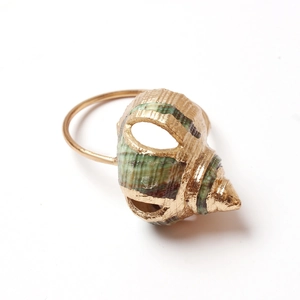 Detailed side view of a conch shell napkin ring with natural green texture and gold rim
