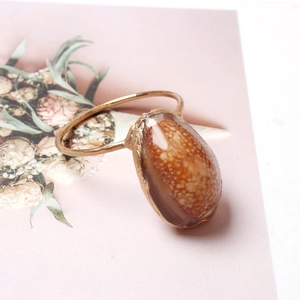 Macro detail of tear-drop shell napkin ring with rustic golden edge on floral card
