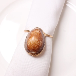 Detailed view of the natural cowrie shell napkin ring on a white linen napkin