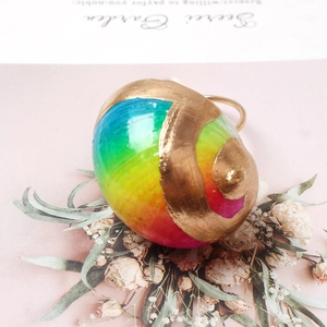 Detail of colorful seashell napkin ring with iridescent coating and golden metallic band