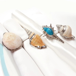 Ocean shell napkin rings set featuring starfish and conch designs with silver metal trim