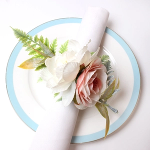 Detailed view of artificial pink and white flower napkin ring on a white linen napkin