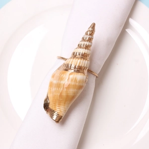 Detail of creative seashell napkin ring featuring natural shell and golden metal bracket