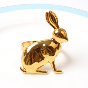 Detailed view of a golden bunny napkin ring on a white plate for festive table setting