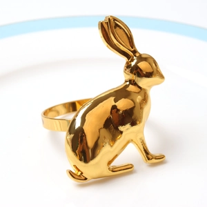 Detail of golden rabbit napkin ring with mirror finish on a white ceramic plate