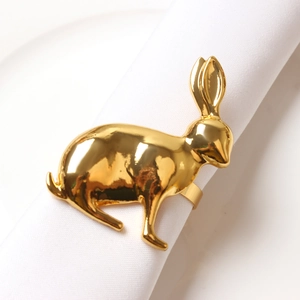 Detail of golden rabbit napkin ring with polished metallic finish on a white cloth