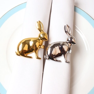 Golden and silver rabbit napkin rings on white ceramic plates for festive table settings