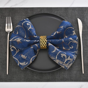 Golden woven mesh napkin ring with wave edges on a navy blue patterned napkin