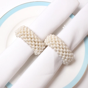 Close-up of elegant woven pearl napkin rings on a ceramic plate for formal dining