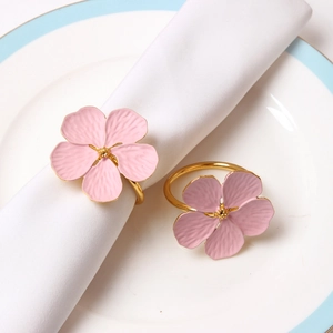Detail of light pink floral napkin rings with gold band and matte metal texture