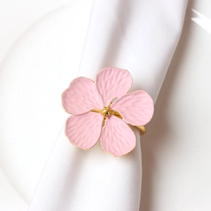 Macro detail of pink flower napkin ring with gold edges on white fabric napkin