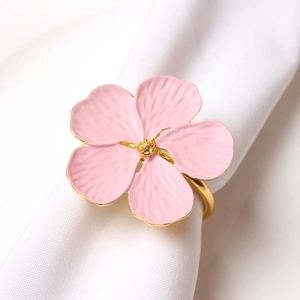 Detail of pink flower napkin ring with gold band on white fabric for table setting