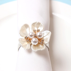 Elegant pearl flower napkin ring with silver metal band on a white dinner napkin