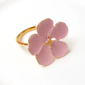 Macro view of light pink plum blossom napkin ring with golden metal ring and lifelike petals