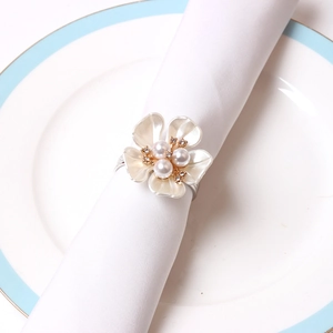 Elegant ivory rose napkin ring with pearls and rhinestones on a white ceramic plate