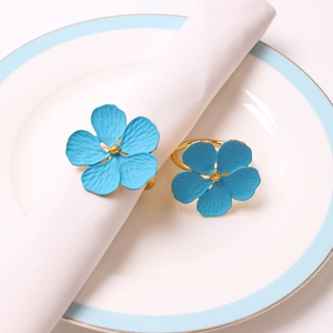 Set of two light blue plum blossom napkin rings with golden metal base on a white plate