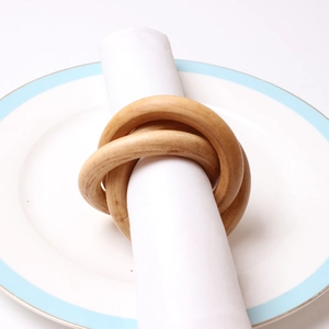 Servilleteros minimalistas de madera entrelazados sobre un plato de cerámica blanco puro