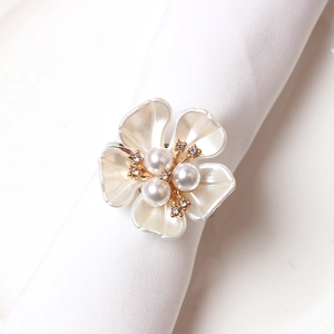 Detail of cream rose petal napkin ring with pearl center and gold metal base