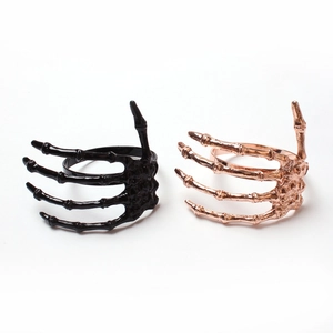 Detailed view of punk style skeleton hand napkin rings in black and rose gold finishes