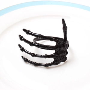 Gothic black skeleton hand napkin ring on a white plate for Halloween table decoration