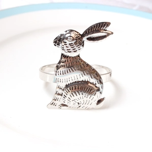 Détail d'un rond de serviette lapin argenté avec gravures rétro sur une assiette