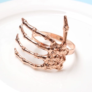 Detailed view of rose gold skeleton hand napkin ring on a white ceramic plate