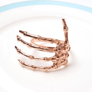Macro view of rose gold metal skeleton hand napkin ring with detailed bone texture