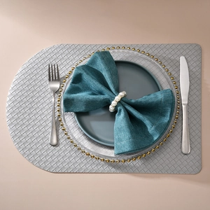 Close-up of elegant handmade pearl napkin ring on blue linen napkin and transparent plate