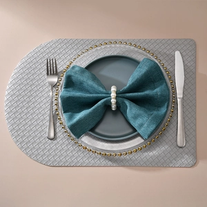 Flat lay of pearl napkin ring on green fabric with woven placemat and cutlery