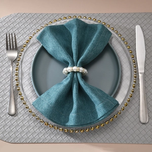 Elegant beaded pearl and rhinestone napkin ring on a navy blue linen cloth napkin