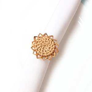Detailed view of handmade rattan sunflower napkin ring on a white linen napkin