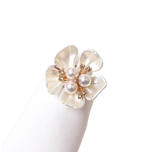 Elegant white flower napkin ring with three pearls and gold edges on a ring holder