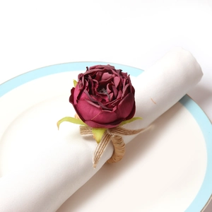 Detail of burgundy peony flower napkin ring with natural hemp woven band on white napkin