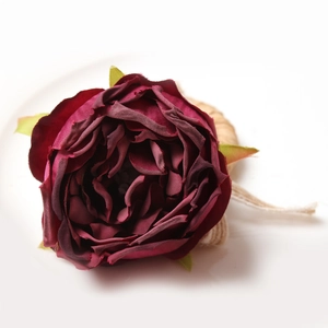 Macro detail of wine red fabric rose napkin ring with rustic jute rope wrapping