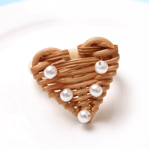 Close-up of heart-shaped woven napkin ring with pearl accents on white ceramic plate