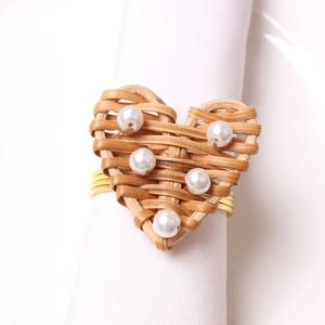 Close-up of heart-shaped rattan napkin ring with white pearls on a gold wire base