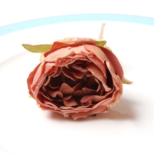 Vintage fabric rose napkin ring in dusty pink on white plate with green leaves