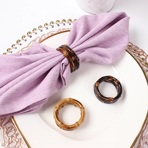 Elegant natural bamboo napkin rings in dark and light brown on a white ceramic dinner plate