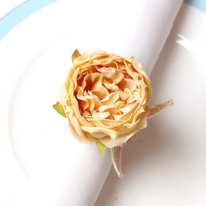 Close-up of champagne peony napkin ring on a white plate with elegant fabric petals