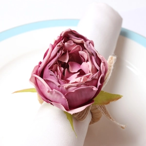 Detail of pink fabric flower napkin ring with woven hemp rope on a white ceramic plate