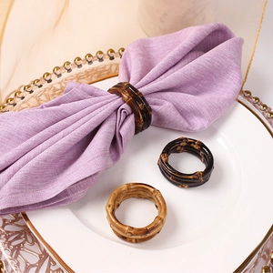 Bamboo-style brown napkin rings on purple linen napkins for elegant table decor