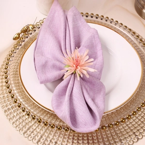 Champagne artificial flower napkin ring on a white plate with gold beaded placemat