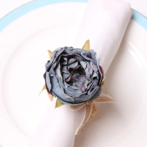 Detail view of a Morandi blue fabric peony napkin ring on a white ceramic plate