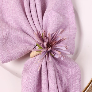 Macro view of a purple artificial flower napkin ring with woven base on a linen cloth