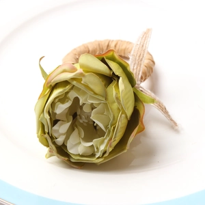 Detailed close-up of a rustic floral napkin ring with a peony and twine loop on a plate
